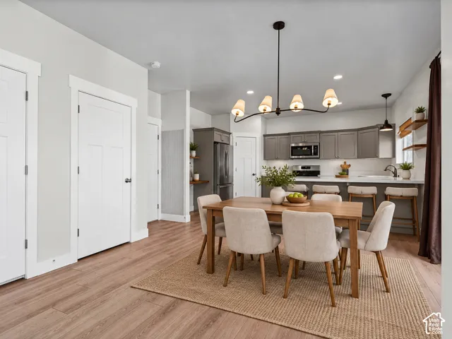 Open-concept living space featuring wood-finish flooring, a modern chandelier, and a kitchen with gray cabinetry, white countertops, and a built-in microwave