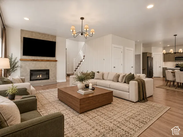 Open-concept living space featuring wood-finish flooring, a contemporary fireplace with a substantial hearth, and a staircase with white balusters