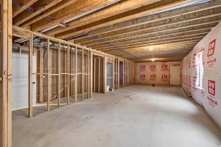 Unfinished basement with exposed wood framing, concrete flooring, and ceiling joists
