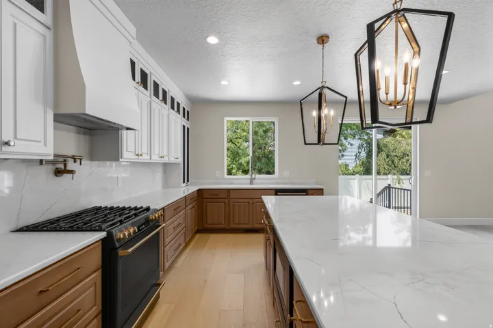 Expansive kitchen with a built-in gas range, white cabinetry, wood-finish lower cabinetry, and recessed lighting
