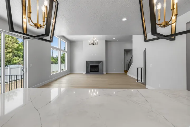 Quartz-finish countertop, wood-finish flooring, fireplace with stone surround, large transom windows, and sliding glass door