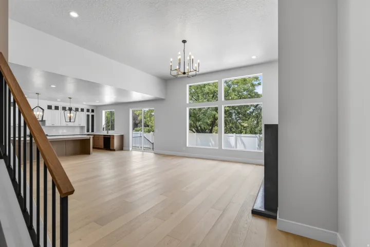 Hardwood-style flooring throughout, an open-concept living space, large multi-pane windows, a sliding glass door, and a modern fireplace