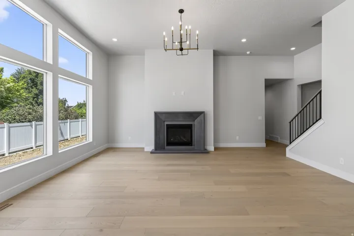 Hardwood-style flooring, a floor-to-ceiling fireplace with dark stone surround, and abundant natural light from multiple large windows
