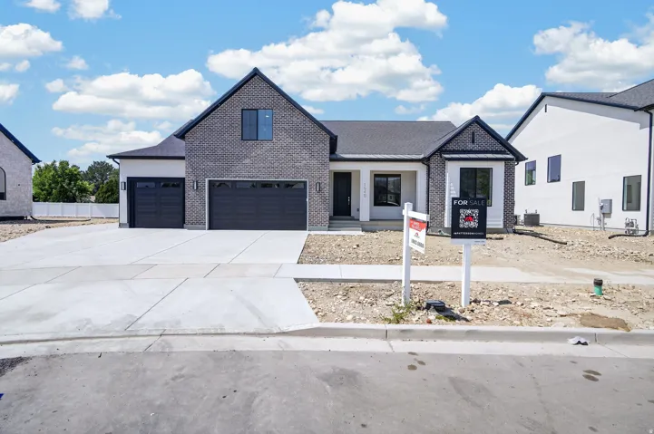 Contemporary exterior with a dark brick facade, black trim windows, a covered entry, and a two-car garage with dark paneled doors