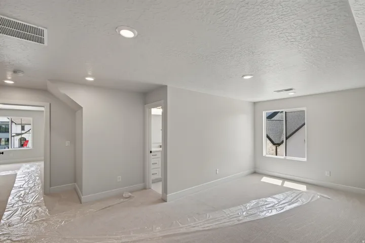 Recessed lighting, light-toned walls, and neutral carpeting