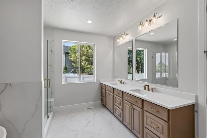 Double vanity with white countertops, integrated sinks, and bronze-finish fixtures
