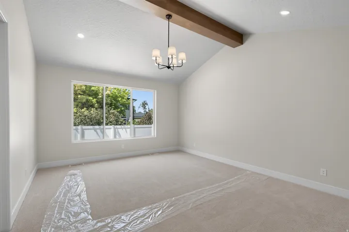 Vaulted ceiling with an exposed wood beam accent, recessed lighting, and a modern chandelier