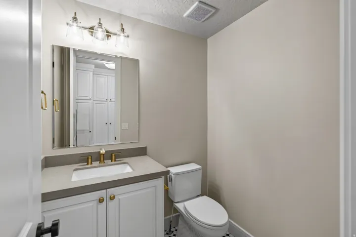 Vanity with white shaker cabinetry, gold-tone hardware, and a gray countertop