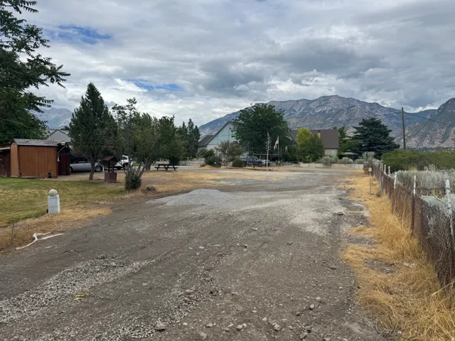 Gravel driveway leading to a residential property with a detached wood-sided shed