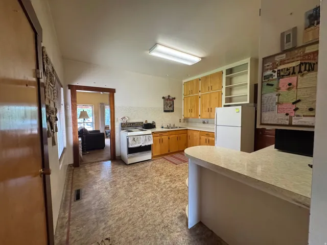 Functional kitchen featuring wood-finish cabinetry, white appliances, and a breakfast bar with a laminate countertop