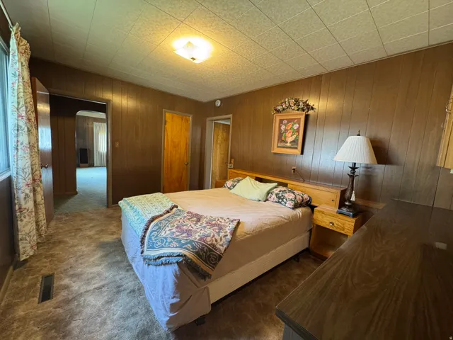 Room featuring wood-paneled walls, a textured ceiling, and carpeting