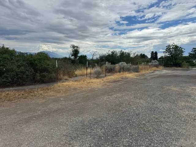 Gravel lot with perimeter fencing and mature shrubbery