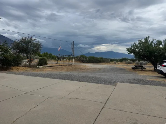Expansive gravel lot with concrete paving, mature trees, and mountain scenery