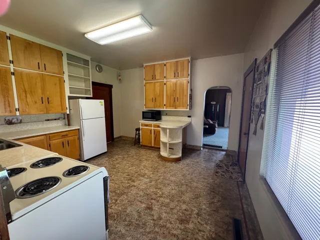Spacious kitchen featuring extensive cabinetry, resilient flooring, and an arched entryway