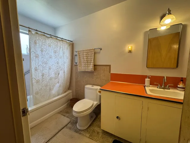 Bathroom featuring a bathtub with shower, toilet, and a vanity with an integrated sink