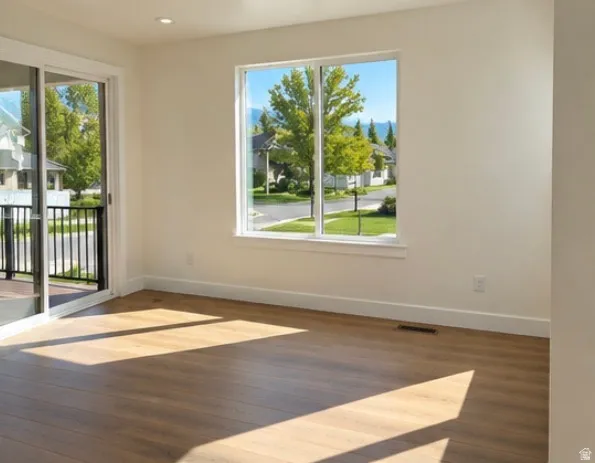 Wood-finish flooring, recessed lighting, white trim, sliding glass door with balcony access, and a large window
