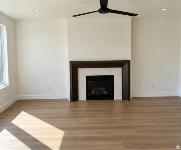 Recessed lighting illuminates the space, featuring wood-finish flooring and a ceiling fan