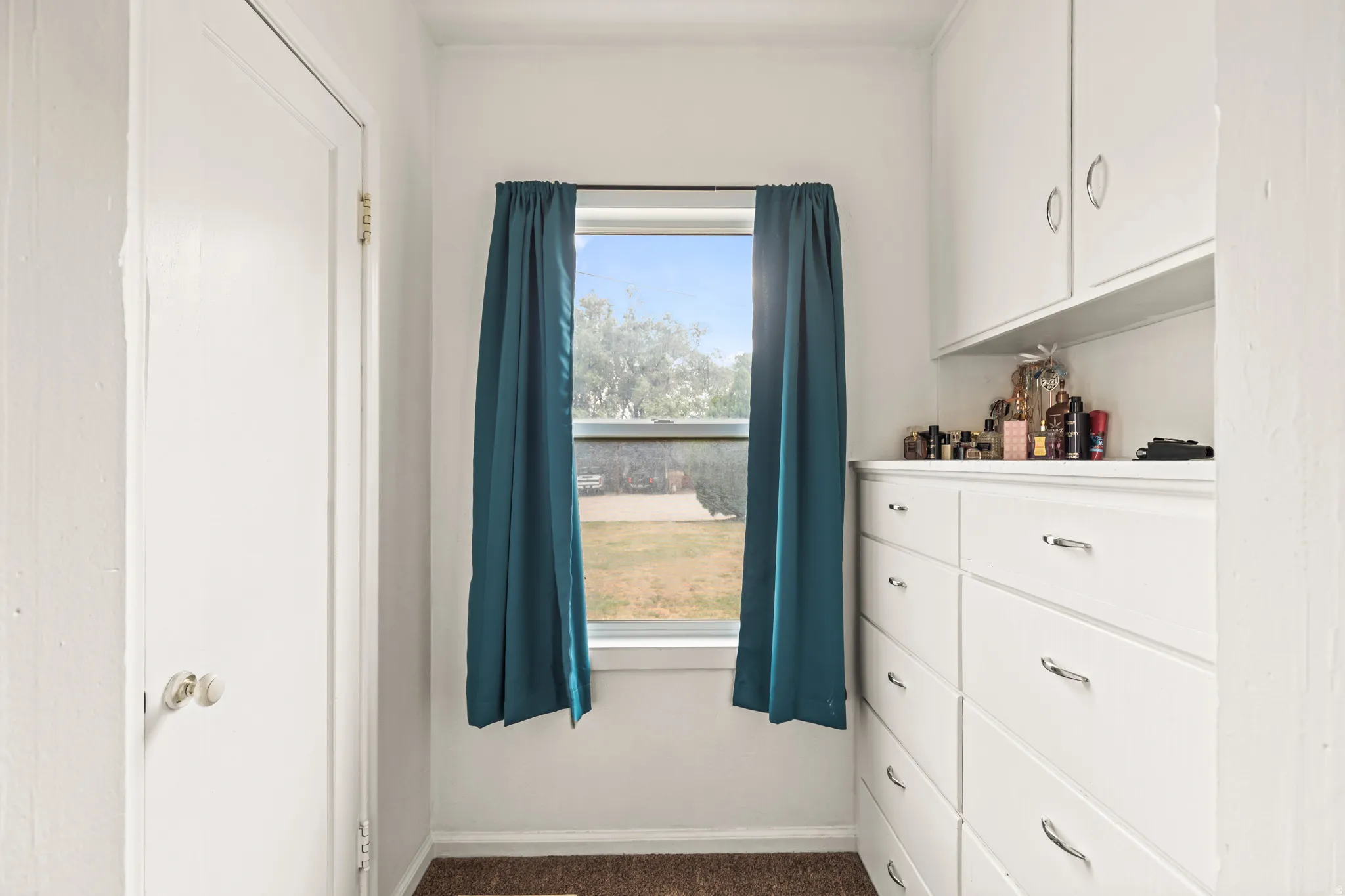 Built-in dresser with chrome hardware, coordinating upper cabinetry, and a window with a green landscape beyond