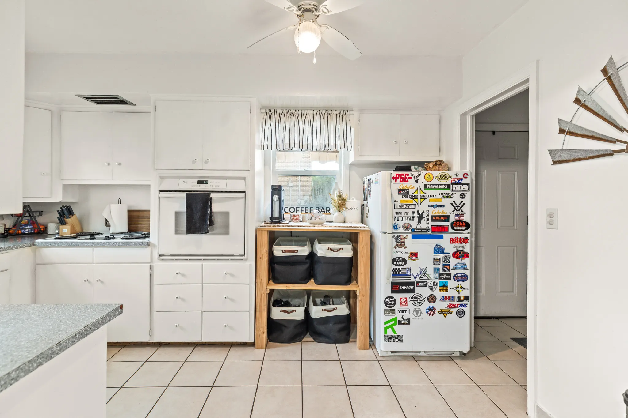 White kitchen featuring an integrated wall oven, white cabinetry, light-toned countertops, and tile flooring