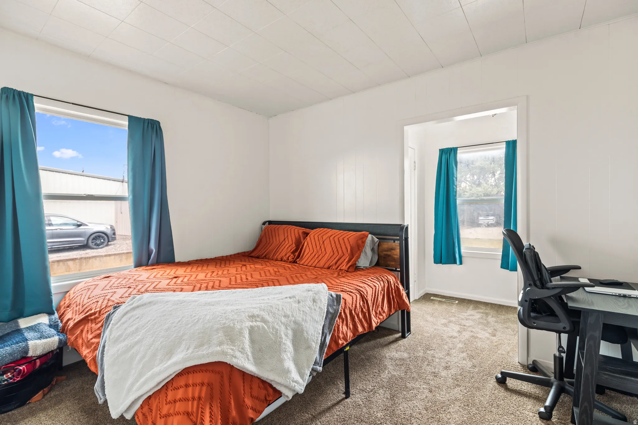 Room featuring a window opening, white paneling, and textured carpet flooring