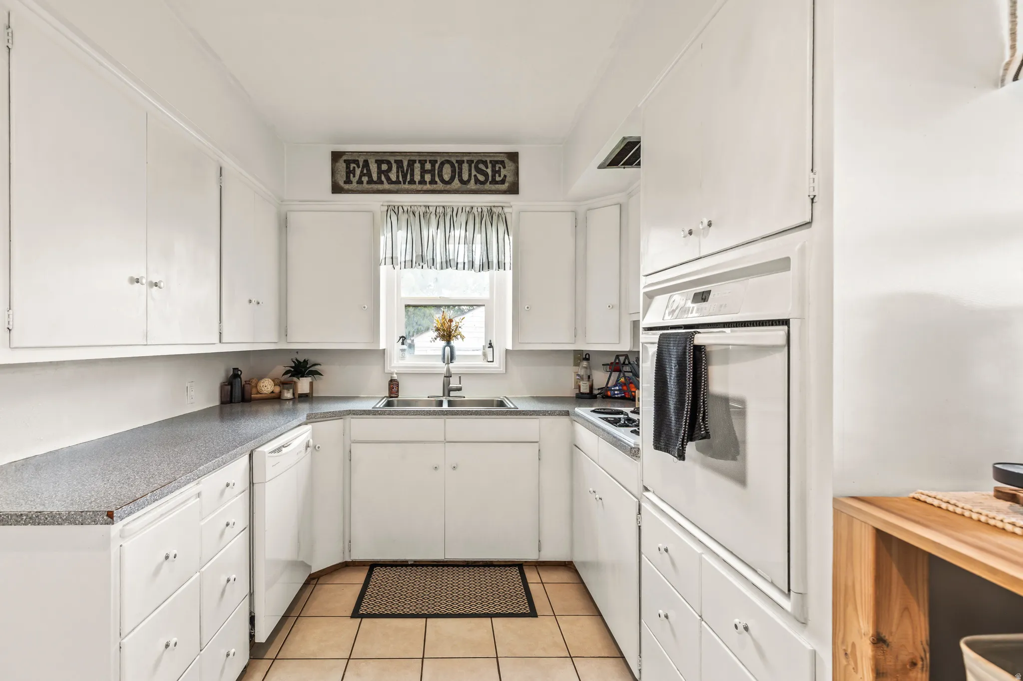 Kitchen featuring white cabinetry, gray countertops, tiled flooring, an integrated wall oven, and a built-in dishwasher