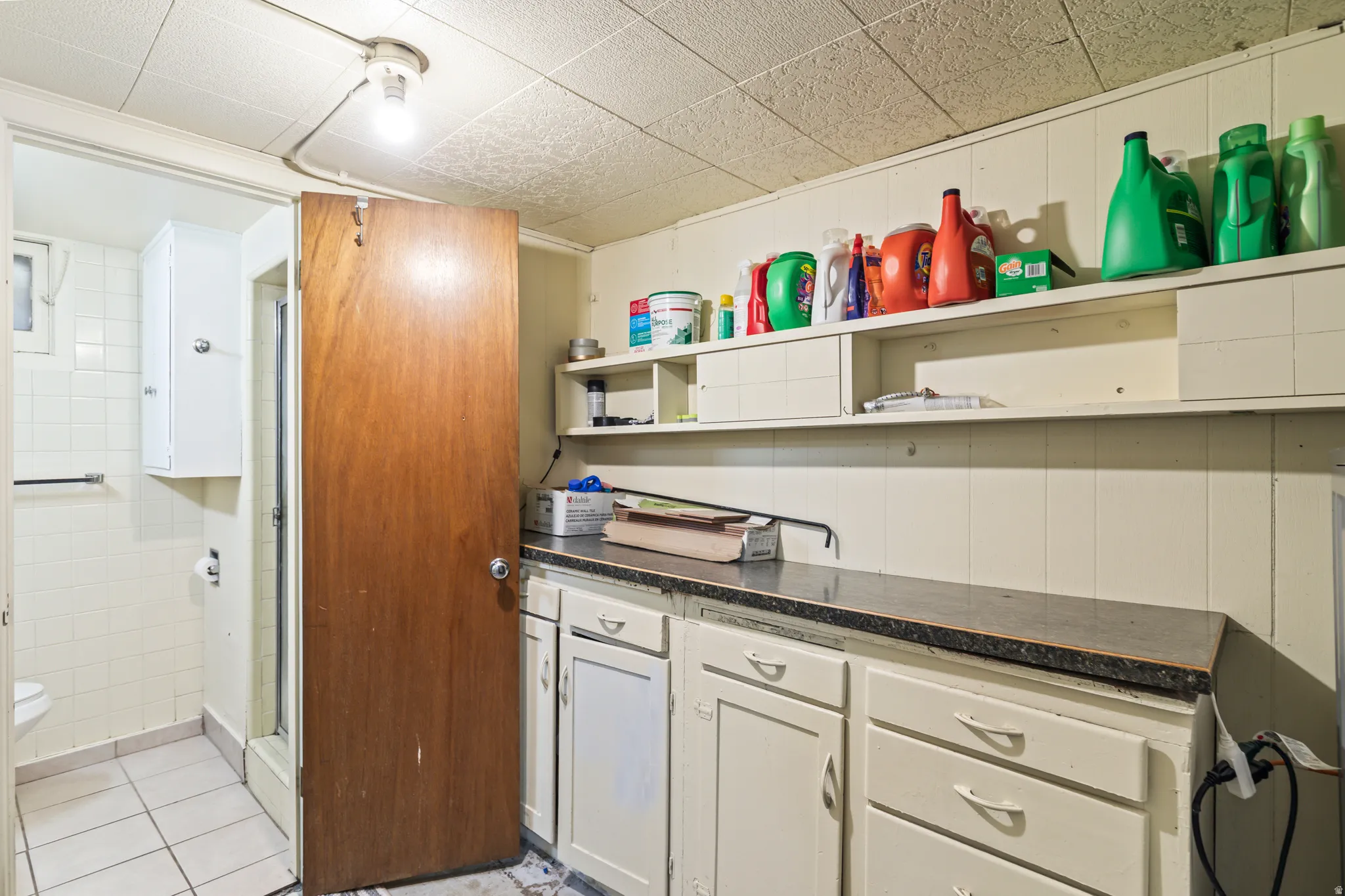 Utility room featuring a built-in countertop with white cabinetry and overhead shelving