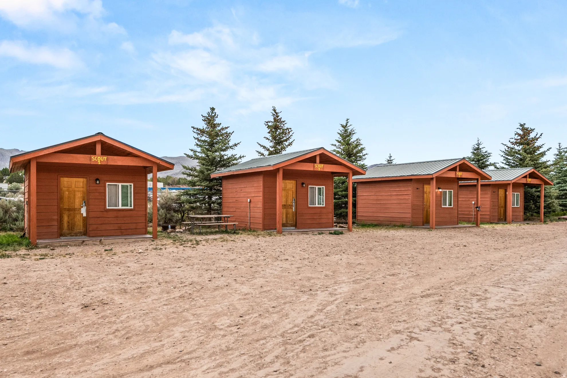 Row of wood-sided cabins featuring covered front porches and individual exterior lighting
