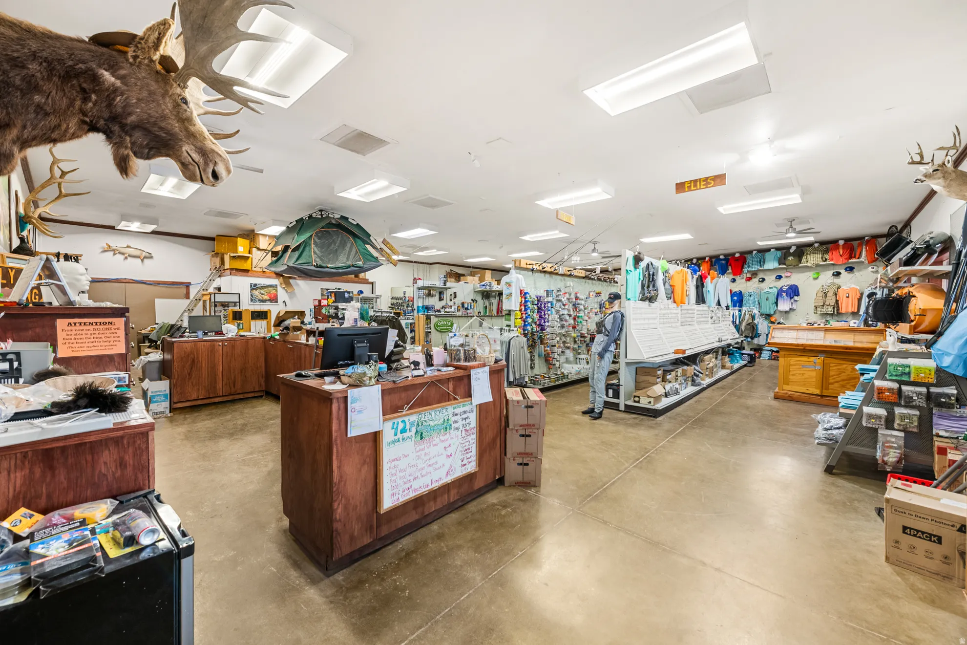 Commercial interior featuring wood-finish counters, extensive display shelving, and recessed ceiling lighting