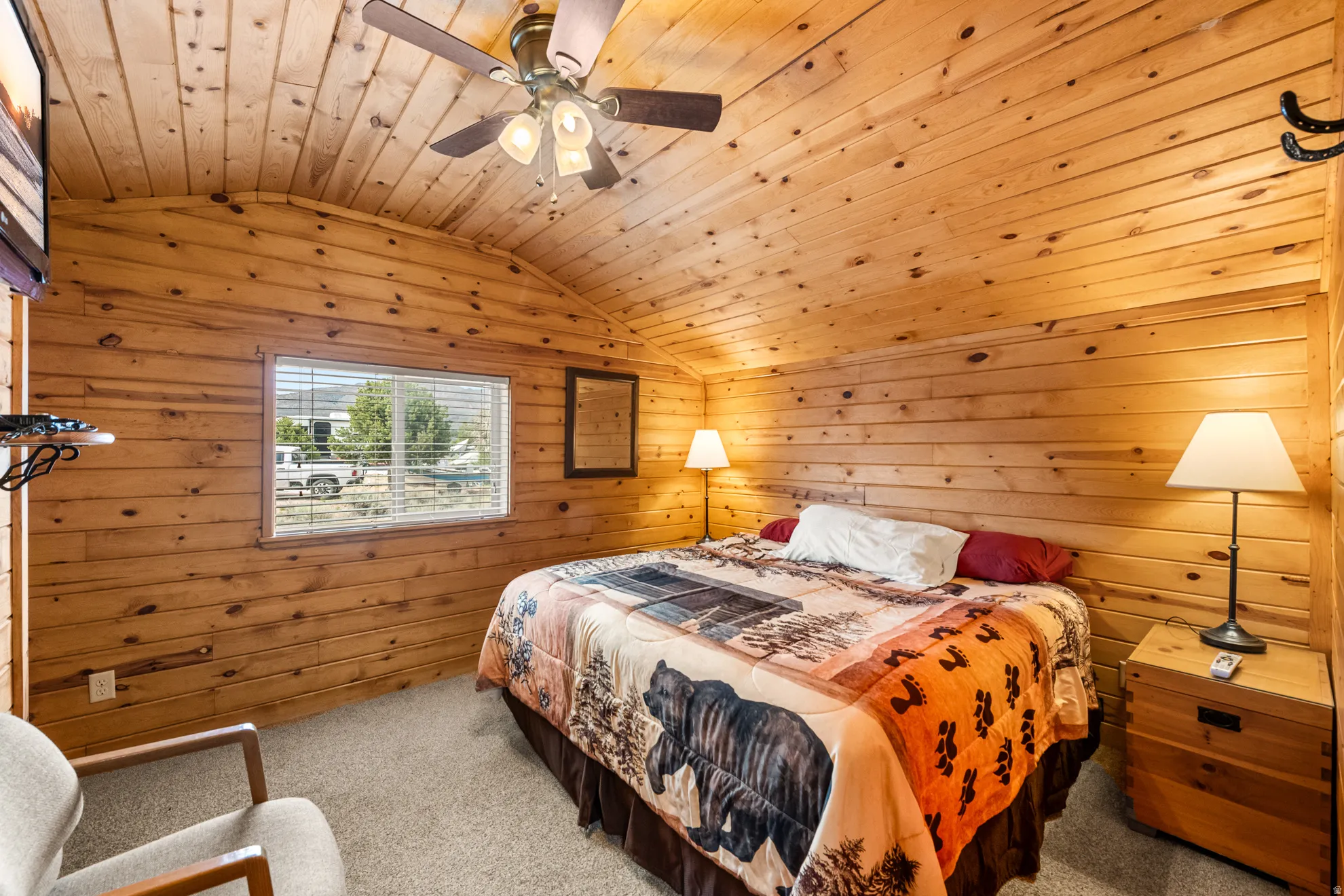 Wood-paneled room featuring a vaulted ceiling with exposed wood beams and a ceiling fan