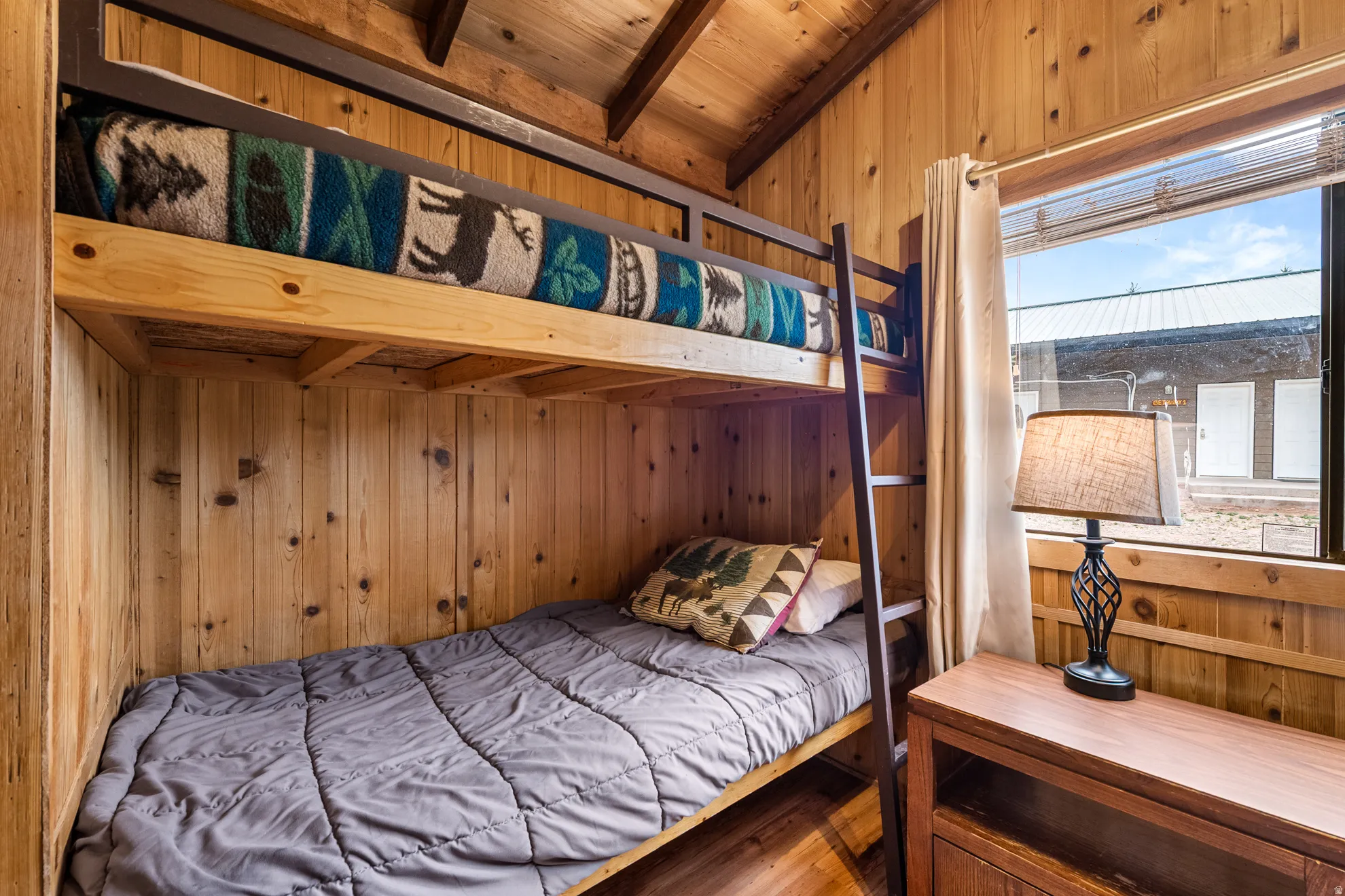 Wood-paneled room featuring built-in bunk beds, sloped wood-paneled ceiling, a built-in wooden cabinet, and a window with blinds