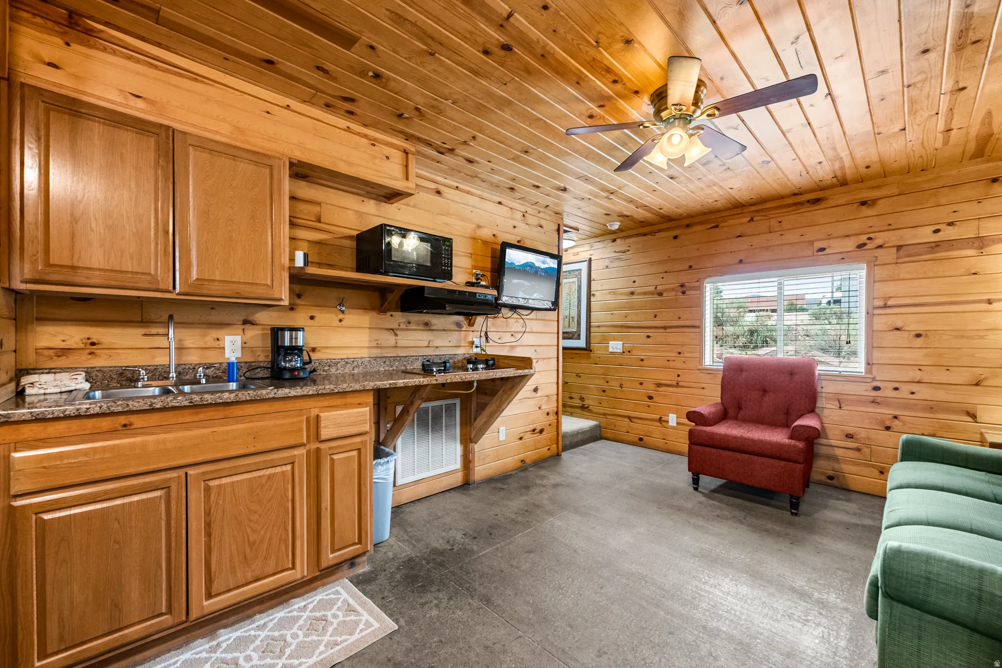 Wood-paneled interior featuring a kitchenette with wood cabinetry, granite-finish countertops, and a stainless steel sink