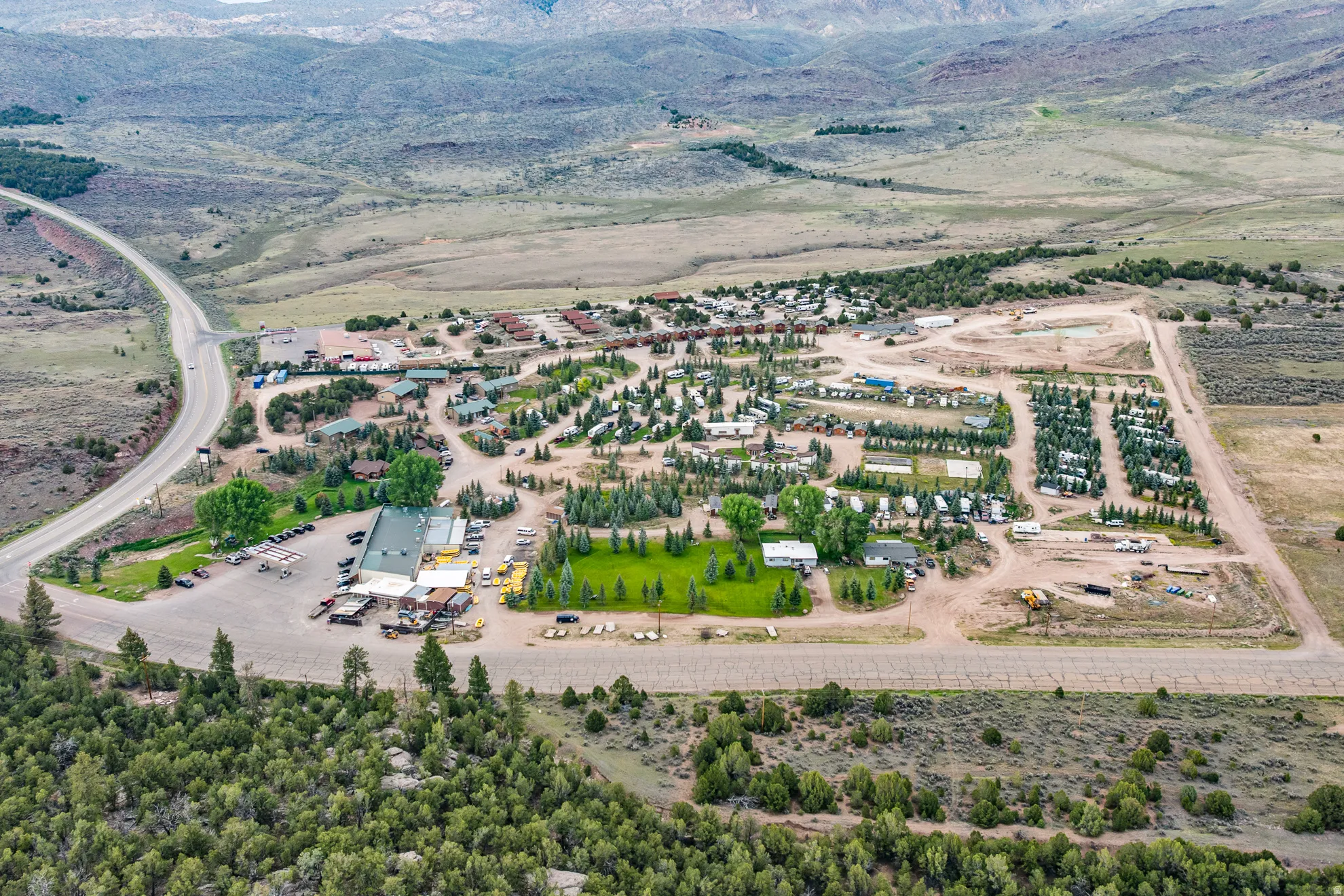 Expansive property featuring a commercial building, multiple RV sites, numerous cabins, substantial undeveloped land, and paved road frontage