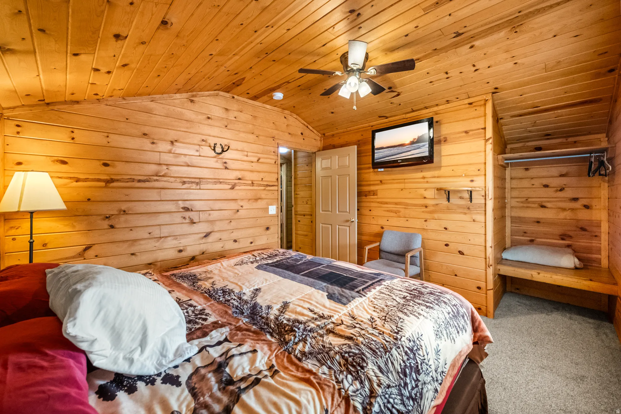 Wood-paneled room featuring a sloped ceiling with a ceiling fan