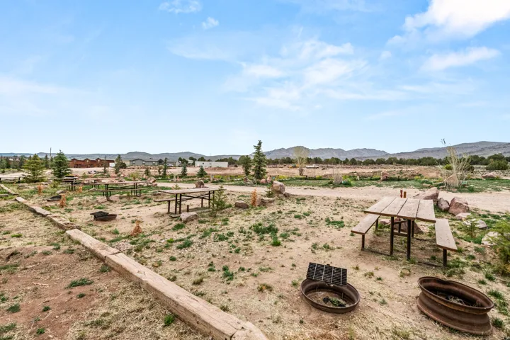 Expansive open area with multiple picnic tables, fire rings, and natural landscaping