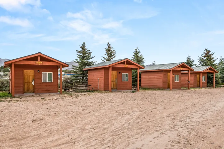Row of wood-sided cabins featuring covered front porches and individual exterior lighting