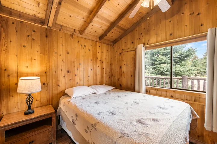 Wood-paneled room featuring a vaulted ceiling with exposed beams