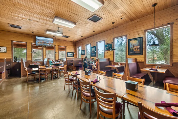 Spacious commercial interior featuring natural wood-paneled walls and ceiling, multiple large windows, and durable concrete flooring