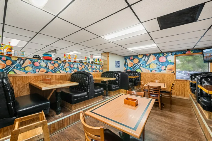 Interior dining area featuring booth seating with black upholstery and wood-finish flooring