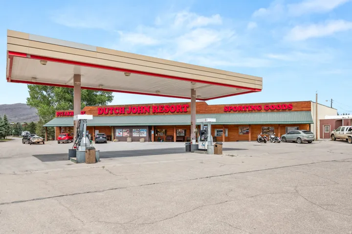 Commercial storefront with a large fuel canopy, multiple fuel pumps, and extensive paved parking