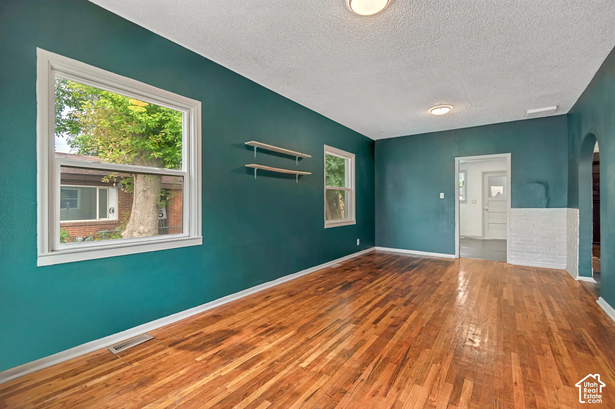 Warm wood-finish flooring complements the deep teal walls in this inviting room
