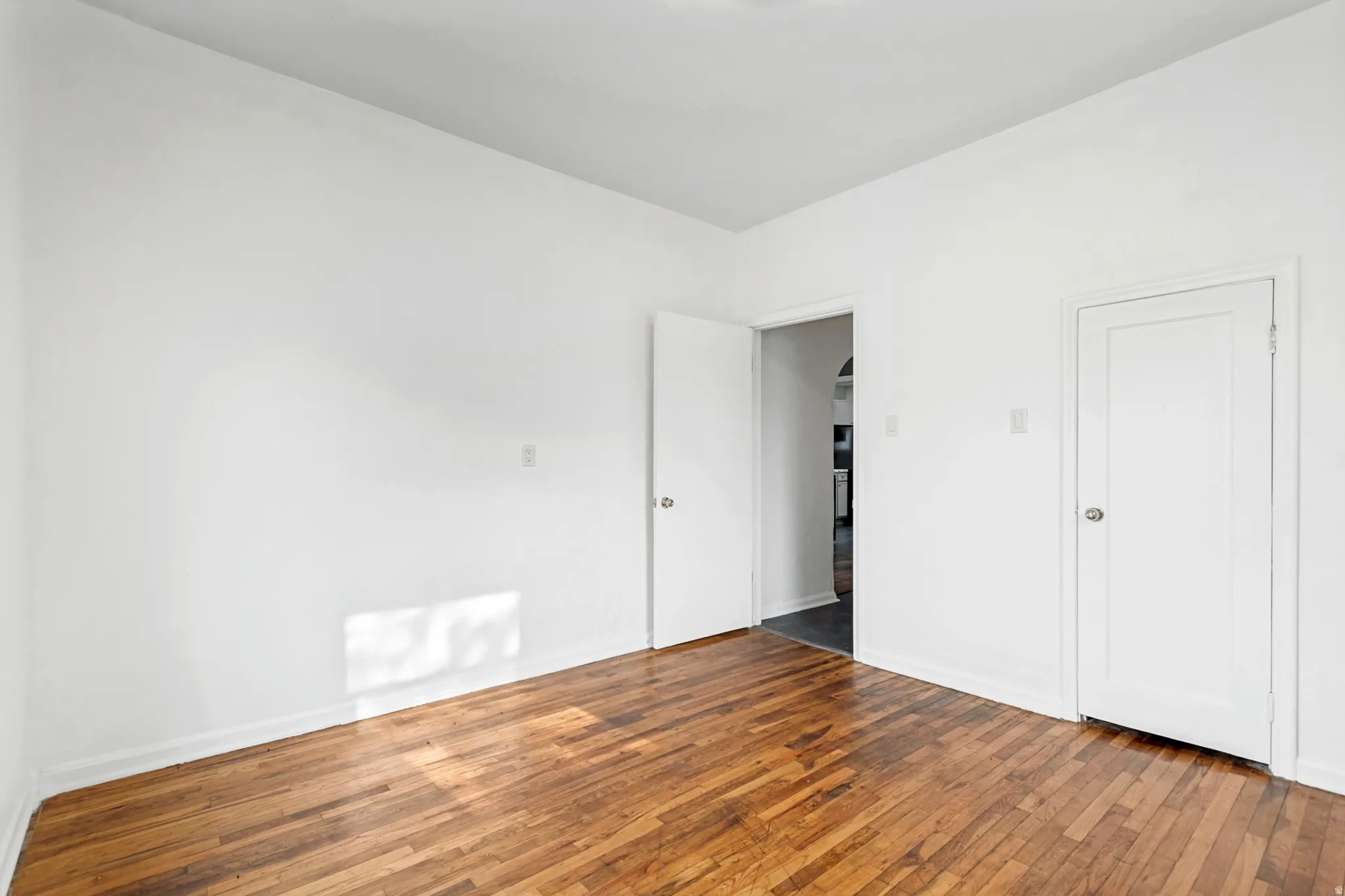 Room featuring wood-finish flooring, white walls, and white trim