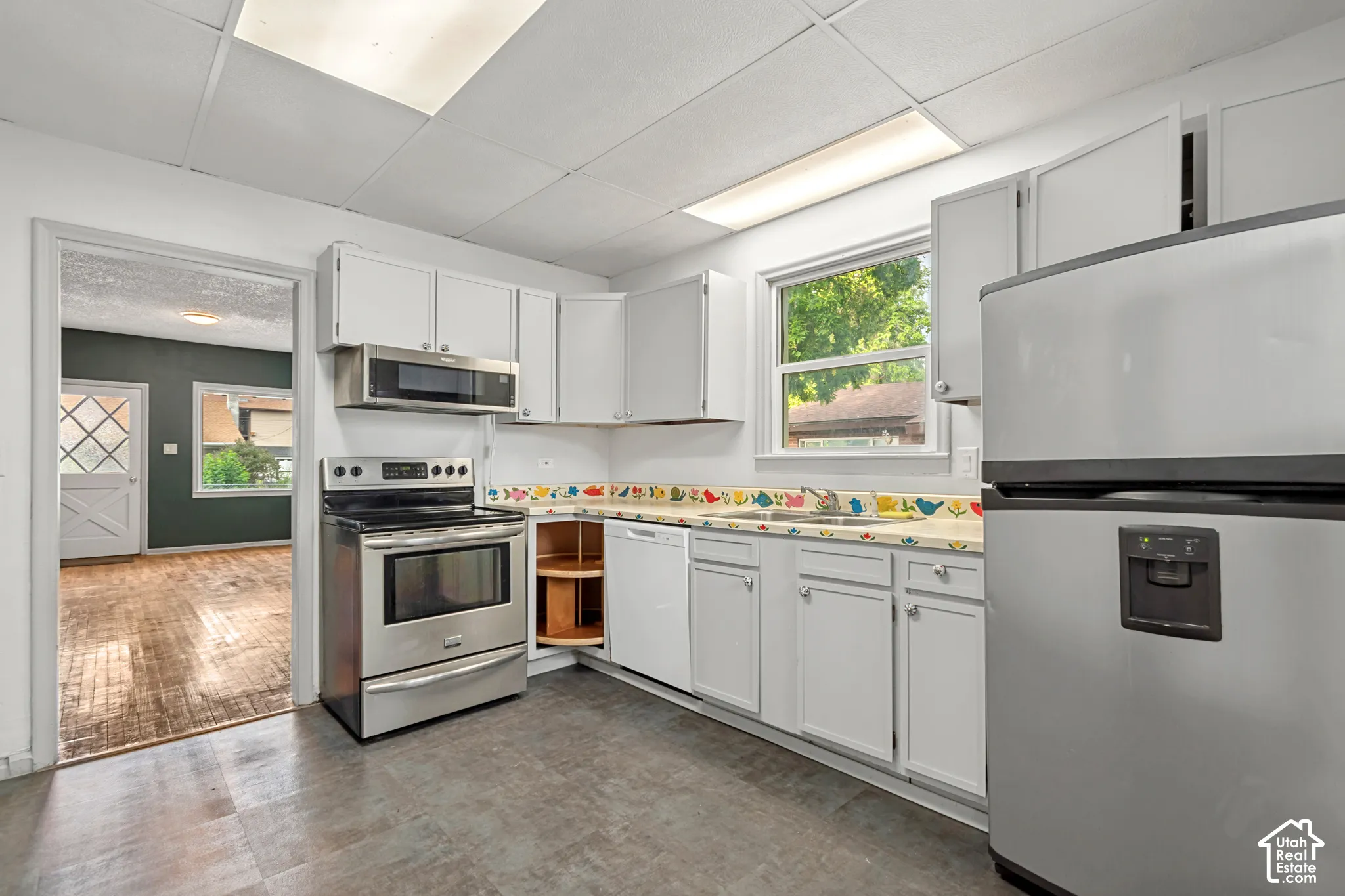 Kitchen featuring stainless steel appliances, white cabinetry, and a window above the sink