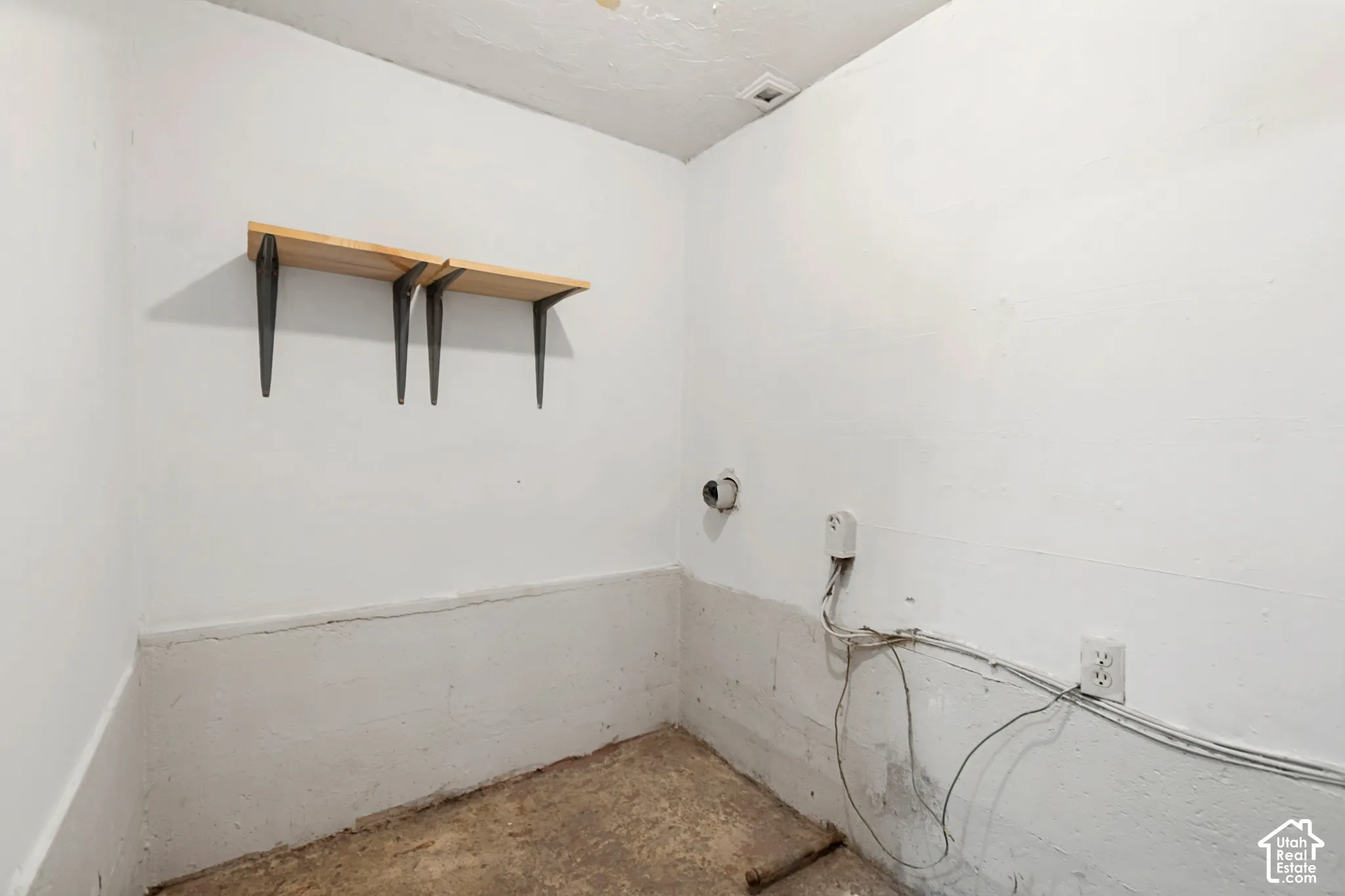 Utility room featuring white painted walls and concrete flooring
