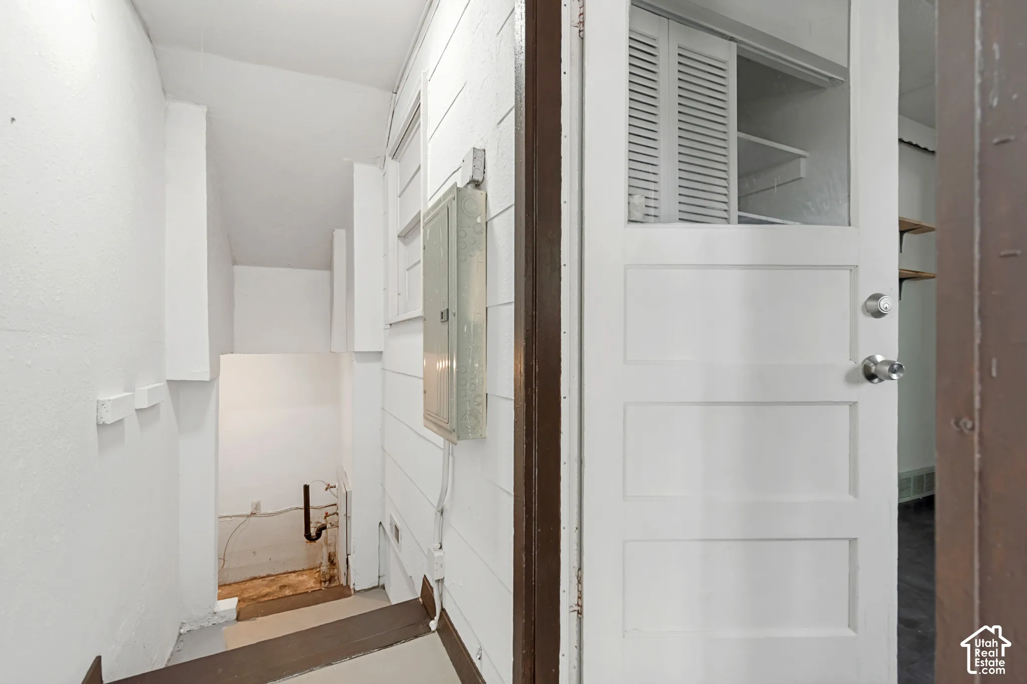 Utility area featuring a panel door with clear pane, a utility panel, and white shiplap wall finishes