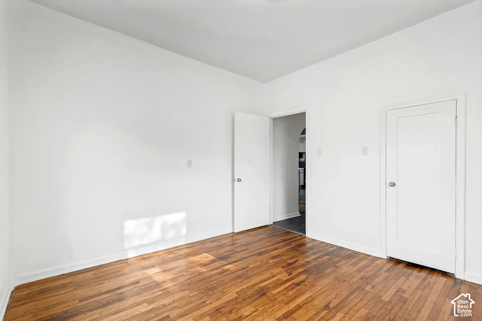 Room featuring wood-finish flooring, white walls, and white trim