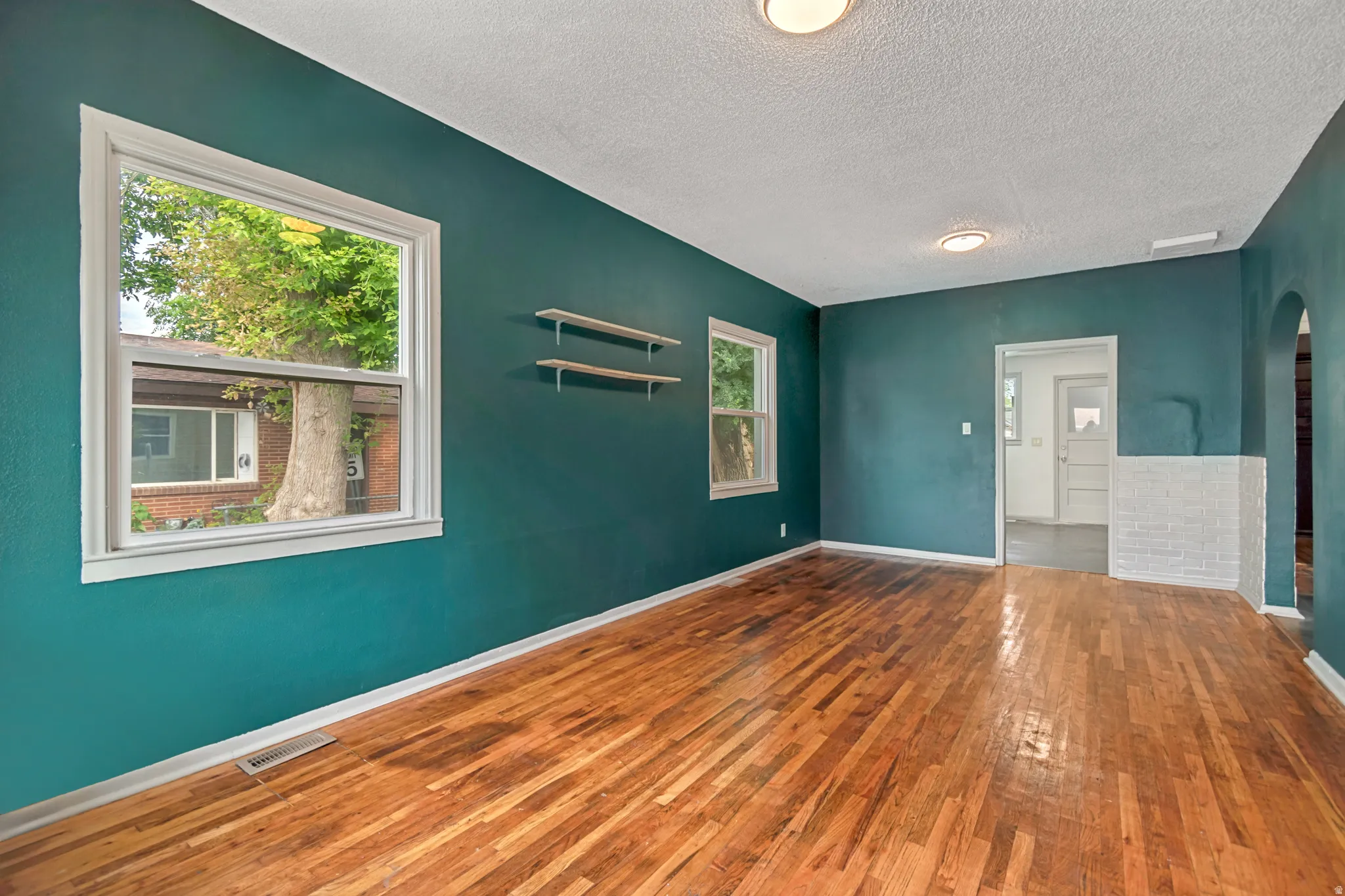 Warm wood-finish flooring complements the deep teal walls in this inviting room