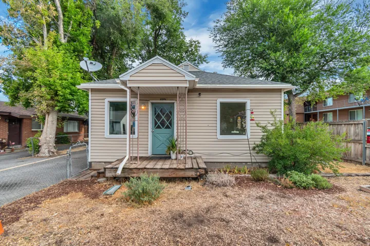 Charming bungalow-style residence featuring beige horizontal siding and a teal entry door with diamond-pane detailing