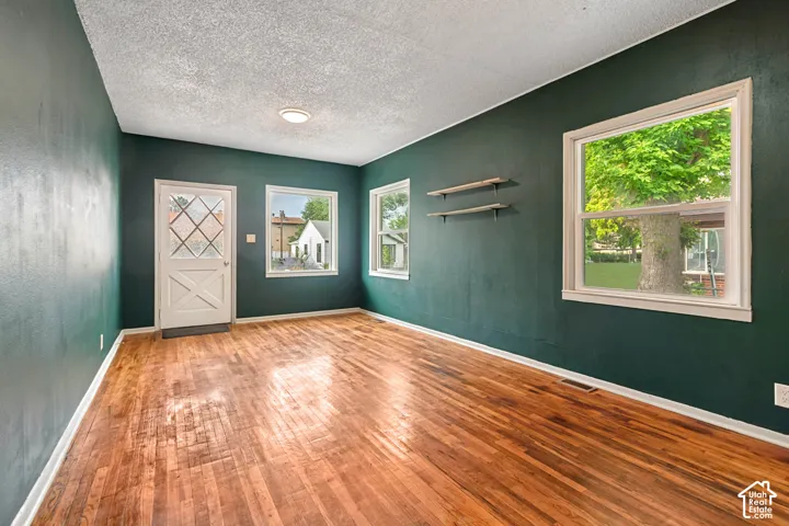 Hardwood flooring throughout a room with deep green painted walls and white trim