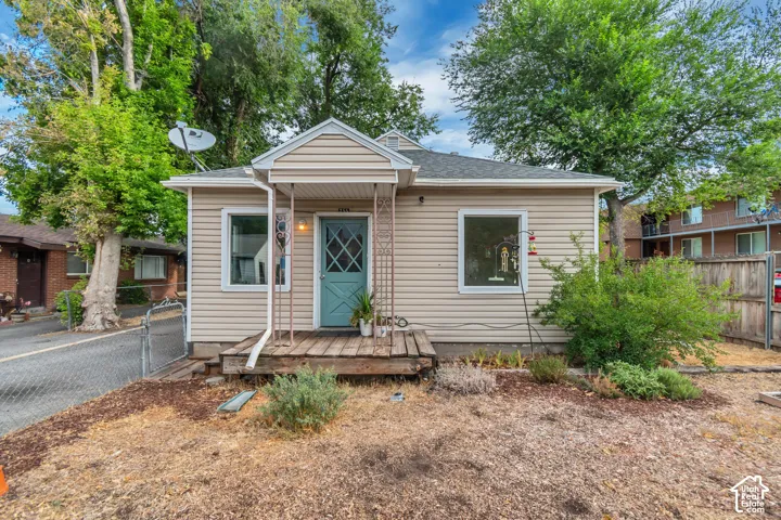 Charming bungalow-style residence featuring beige horizontal siding and a teal entry door with diamond-pane detailing