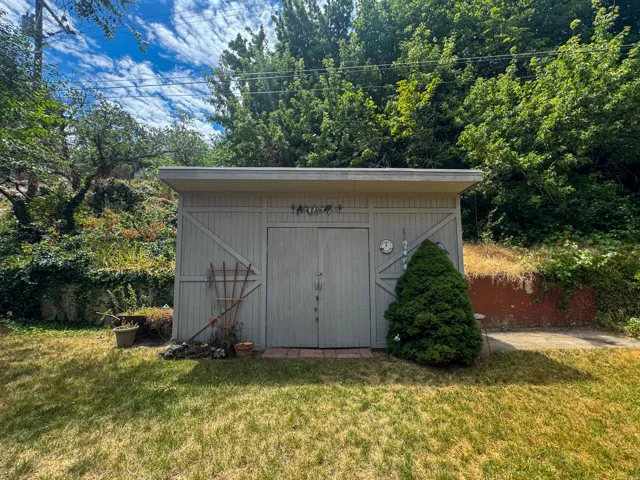 Detached shed featuring double barn doors and an adjacent paved area